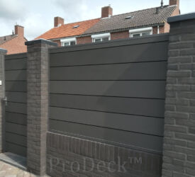 De kleur van de antracieten stapelplanken past meer dan goed bij de kleur van de stenen van de gemetselde beertjes. Ook de tuindeur is met stapelplanken in elkaar gezet. Stapelplank schutting • antraciet • extra hoge planken