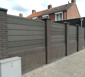 Extra hoge stapelplanken kunnen prima tussen gemetselde muurtjes en beertjes geplaatst worden. In dit geval ook nog eens qua kleur passend bij de kleur van de stenen. Stapelplank schutting • antraciet • extra hoge planken